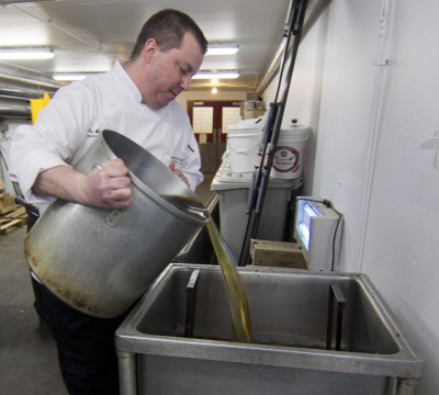 Dan Watrin, executive chef at Bon Appétit on Cornell’s campus, pours oil that will be used to make biodiesel. 