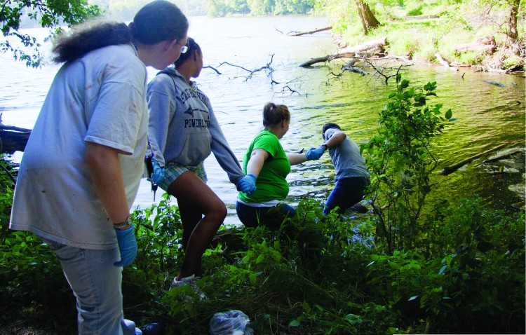 Students reach out to pull an old tire out of Lake MacBride during New Student Orientation Service Day in 2010 (Photo by Jamie Kelly)