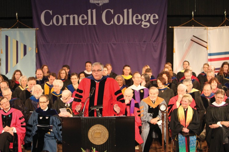 With the faculty seated on stage behind them, John Smith '71 introduces President Brand.