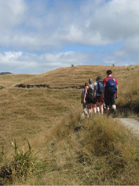 Geology students set off toward Wharariki Beach on the South Island, New Zealand, to examine the cross section of exposed rock cliffs on the beach.