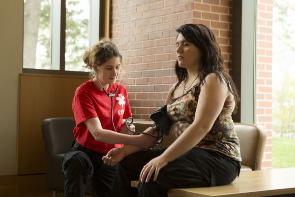 Sabine Hahn ’18 demonstrates on a patient model in the Thomas Commons. (Photo by Envisage Studios) 