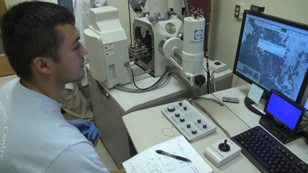 Carlos Tellez works with a scanning electron microscope