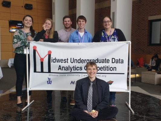Cornell students posing by sign at a data analytics competition