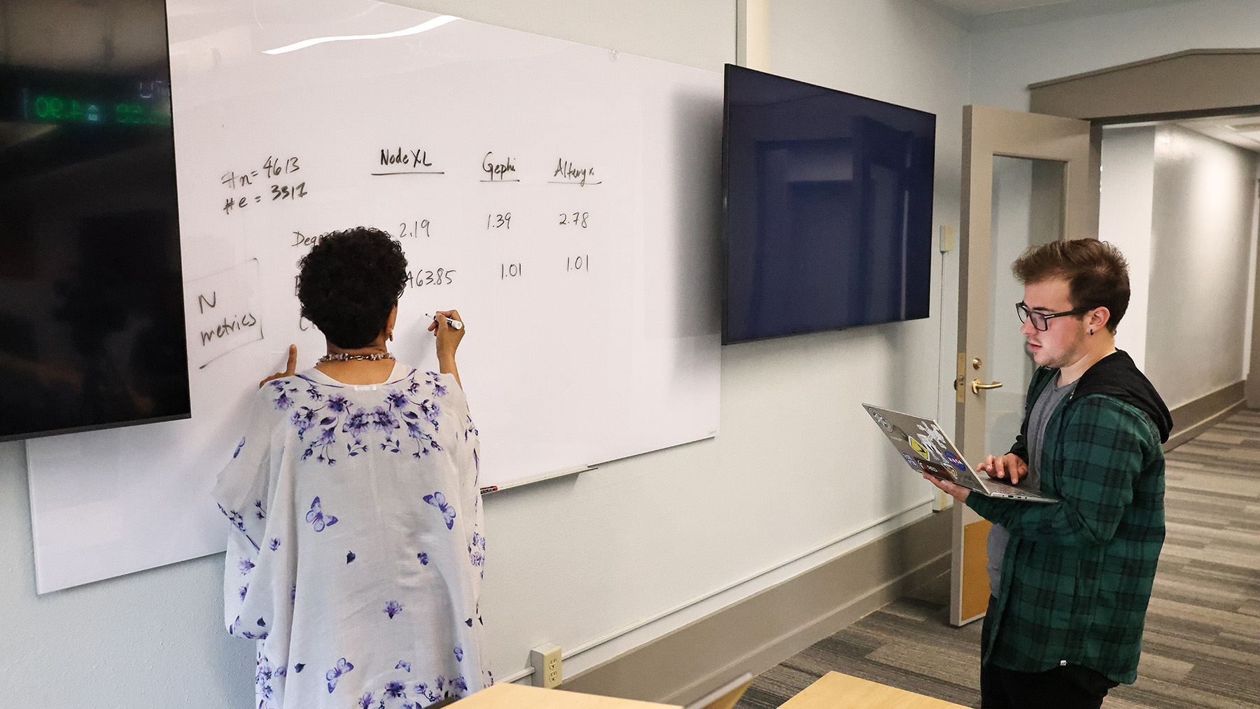 A student and a professor work together at a white board.