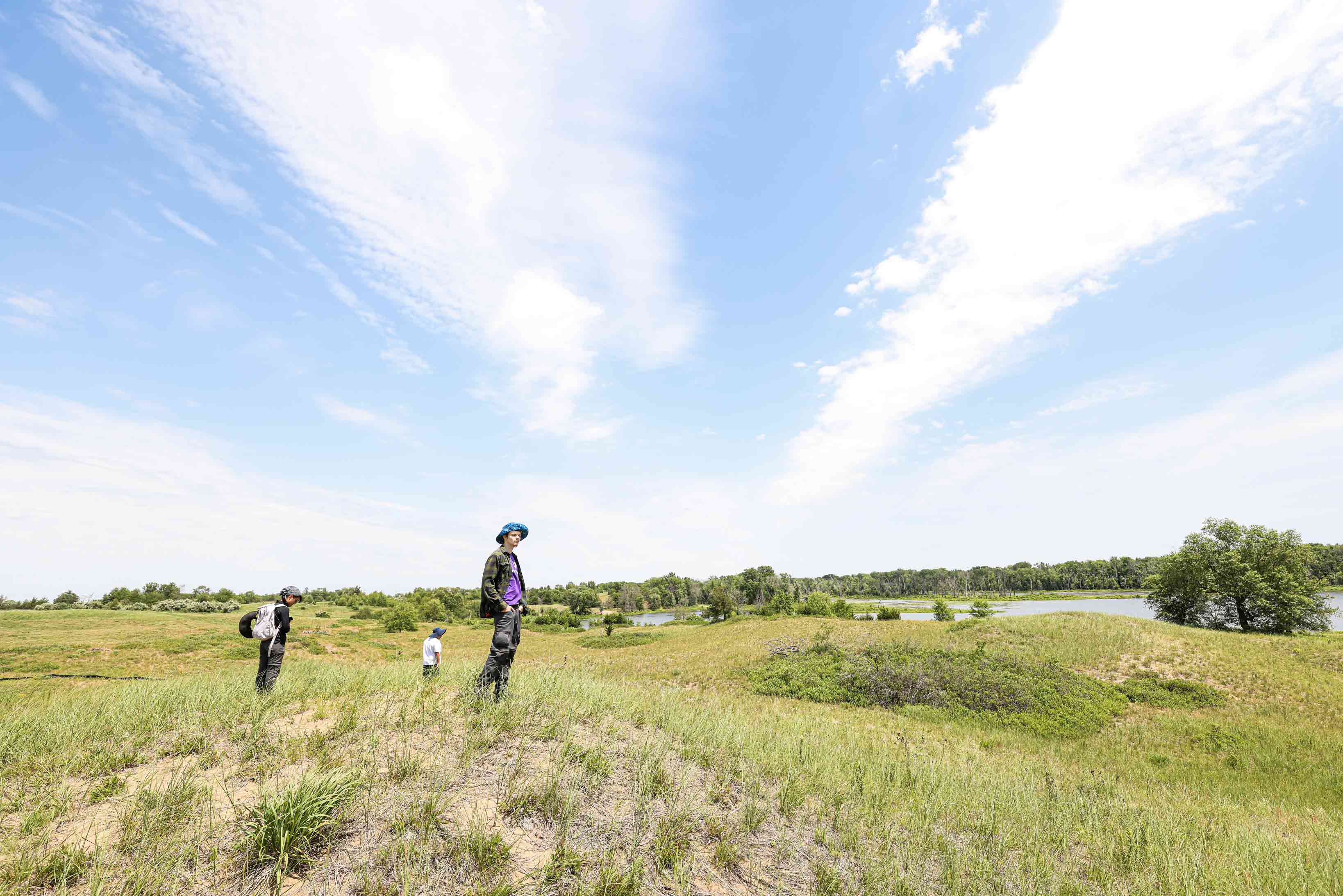 Three students explore a nature preserve on a sunny day.