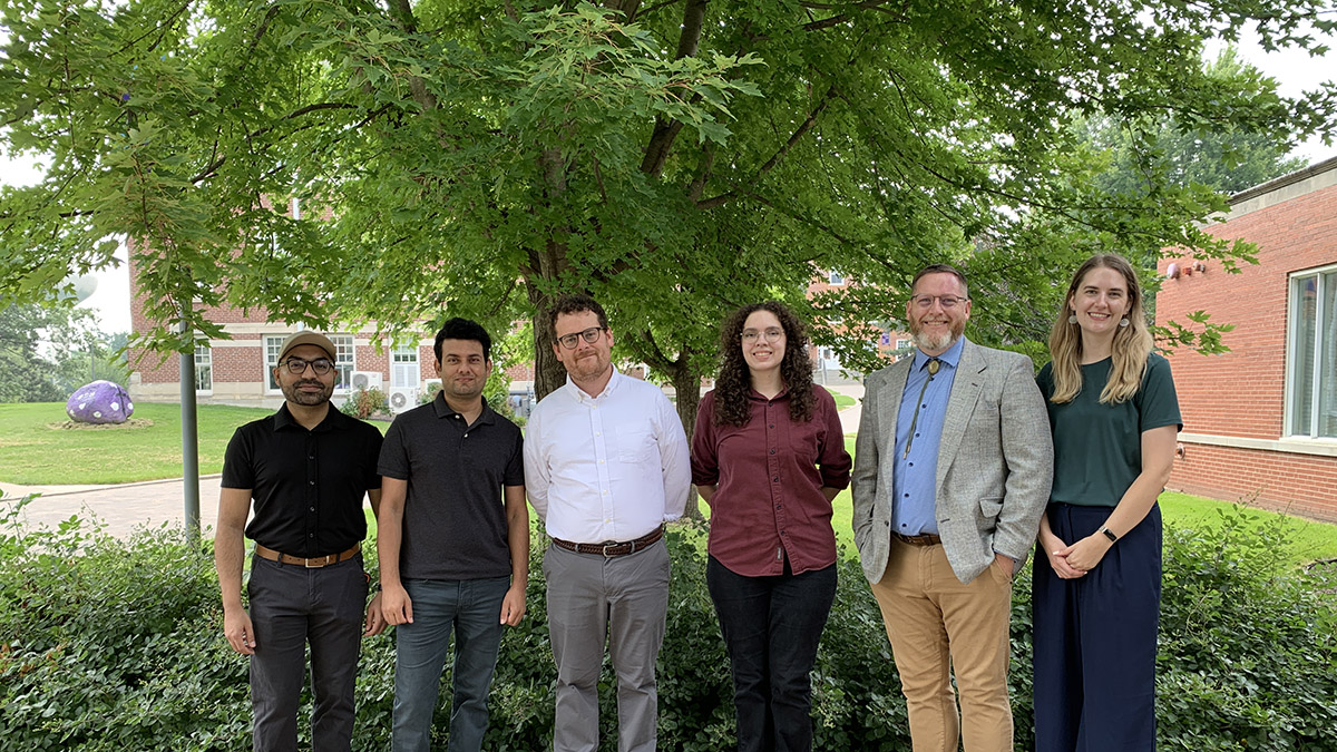 6 new faculty stand in front of Cole Library on Cornel campus