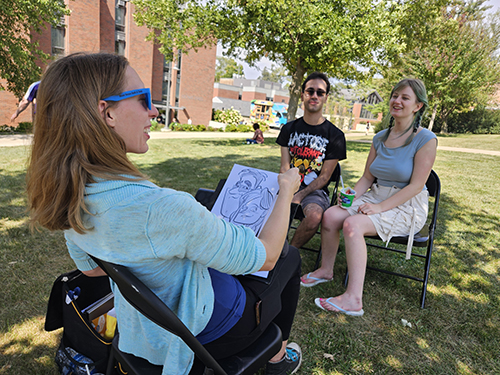 two students get drawn by a caricature artist.
