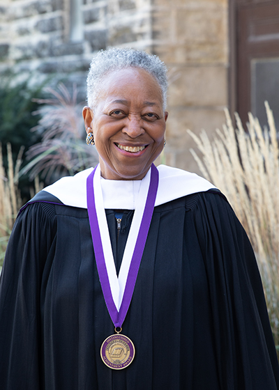 Madgetta standing in her Convocation robe.