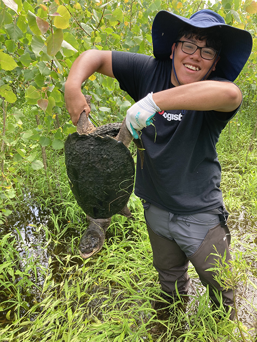 Jason Ramos holds up a large snapping turtle.