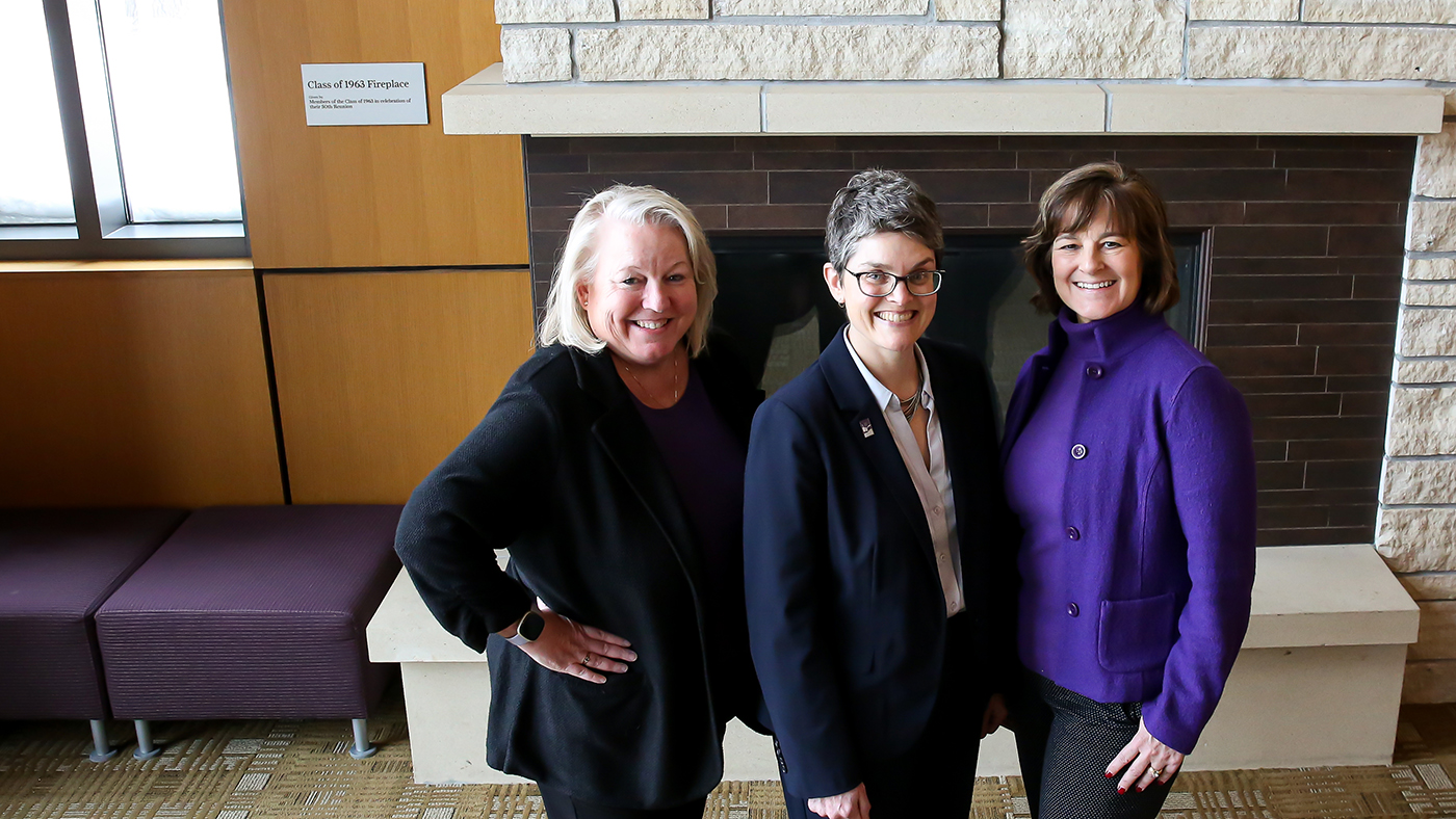 Cornell's three female vice-president's stand in front of the fireplace at Thomas Commons