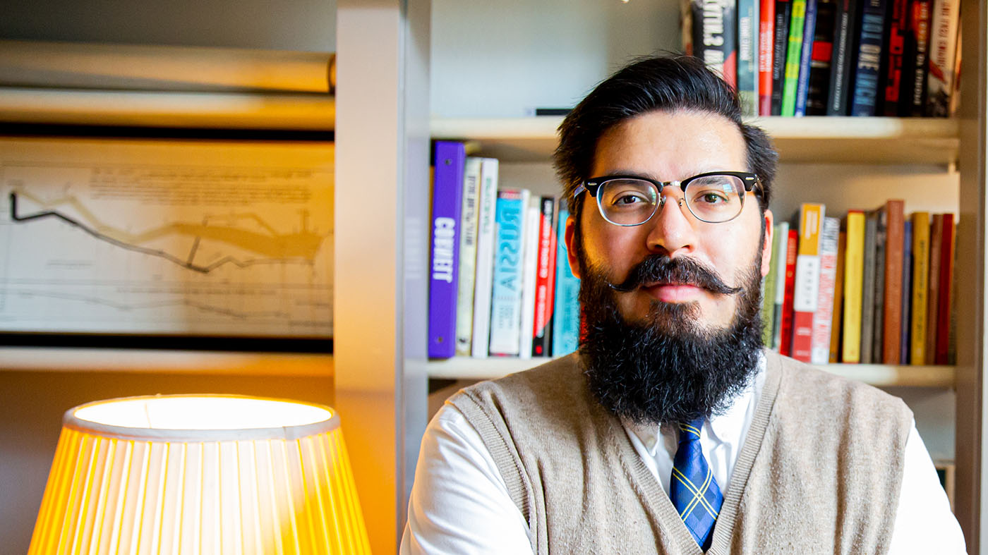 Assistant Professor of History Jonathon Dreeze pauses in front of his bookcase for a photograph