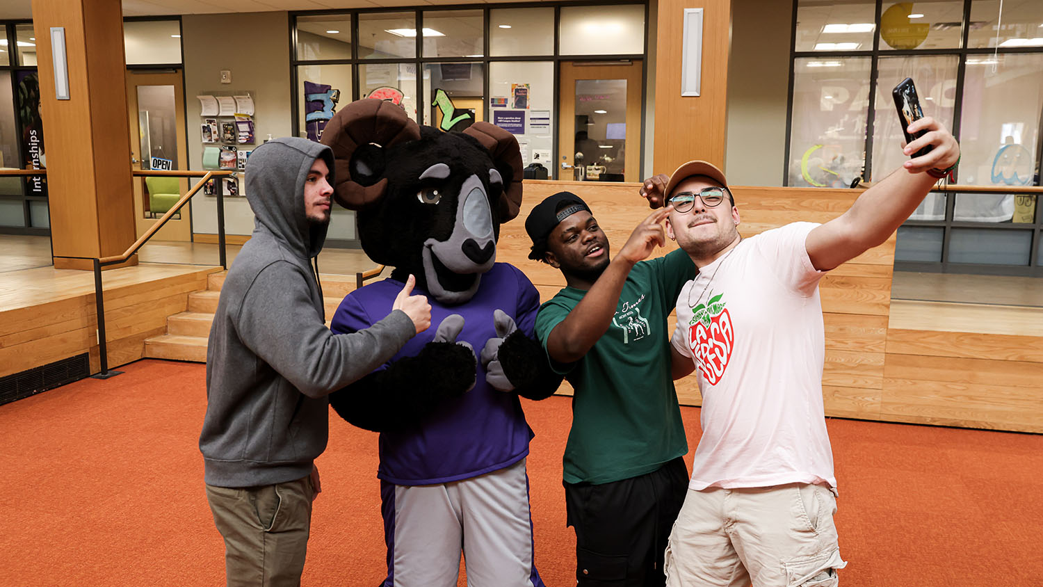Cornell College mascot Ulysses the ram poses for a selfie with three students.
