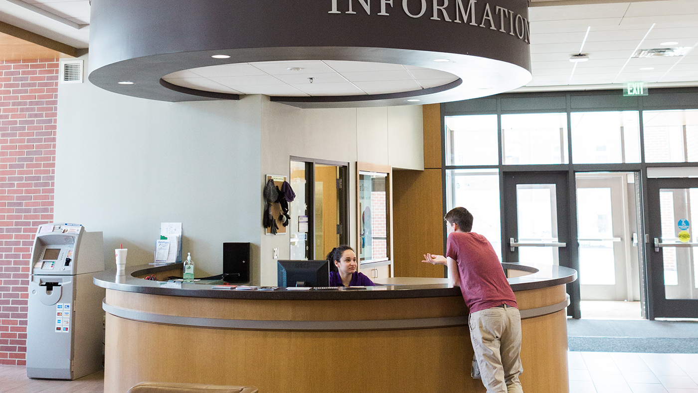 Two people chatting at the Cornell College information desk.