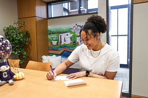 Washington writes a note to a student in the Welcome Center.