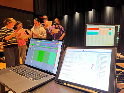 Students stand in front of audio recording equipment.