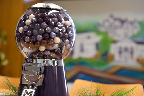 A purple gumball machine with purple and white gumballs