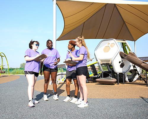 Four students taking notes on a playground.