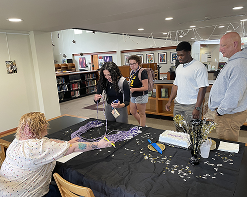 Students take special graduation cords and cake during a first-generation graduation event.