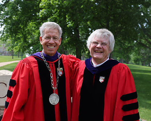President Brand and Professor Lucas pose together in their Cornell University graduate school robes