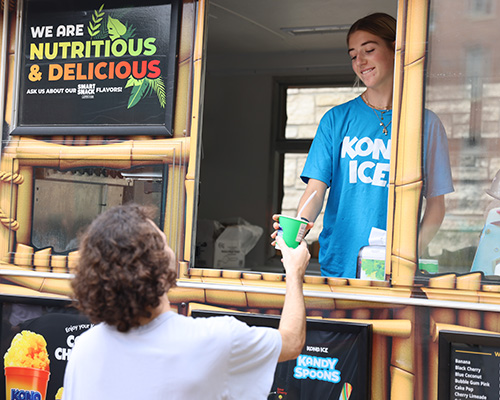 A Cornell student receives a snow cone from the Kona Ice truck at Ramapalooza.