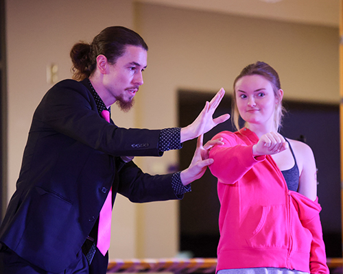 Magic John performs a trick with a student volunteer.