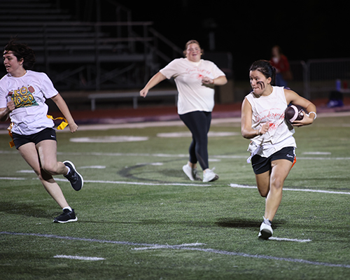 A student runs with the football during Homecoming 2025's powderpuff game.