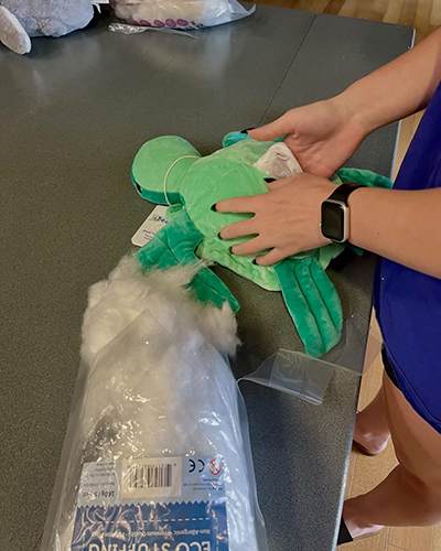 A student puts stuffing into their turtle stuffy.