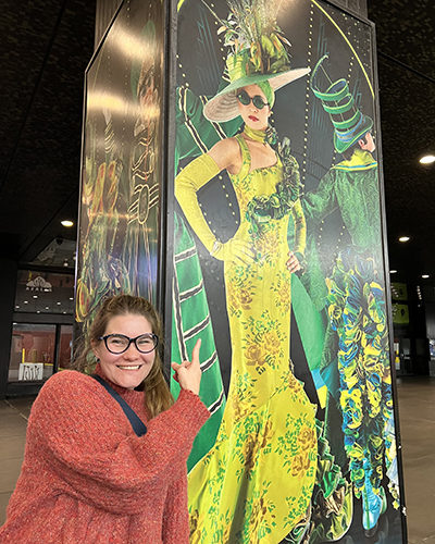 Amanda Kai Newman pointing to a hat she built for the Australian production of Wicked.