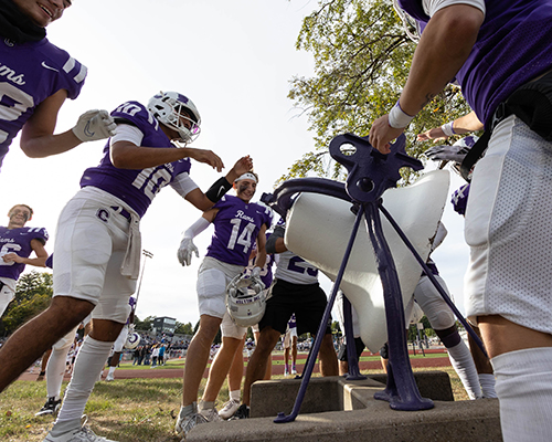 Cornell football players take turns ringing the victory bell following a 36-24 Homecoming win over Beloit on Oct. 7, 2023.