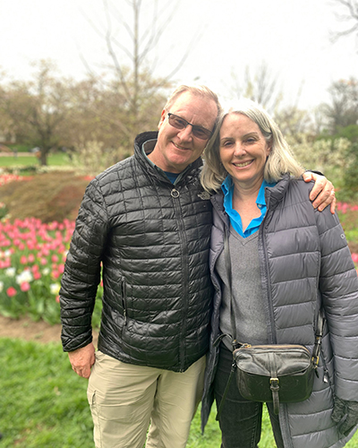 Dan Brennan and Susan Kozal Brennan stand among flowers