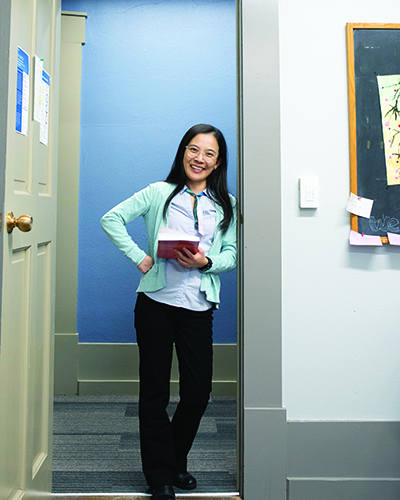 Associate Professor of Finance Huan Cai stands in the doorway of her McLennan College Hall office. Support from the endowment has helped her pursue student-faculty research.