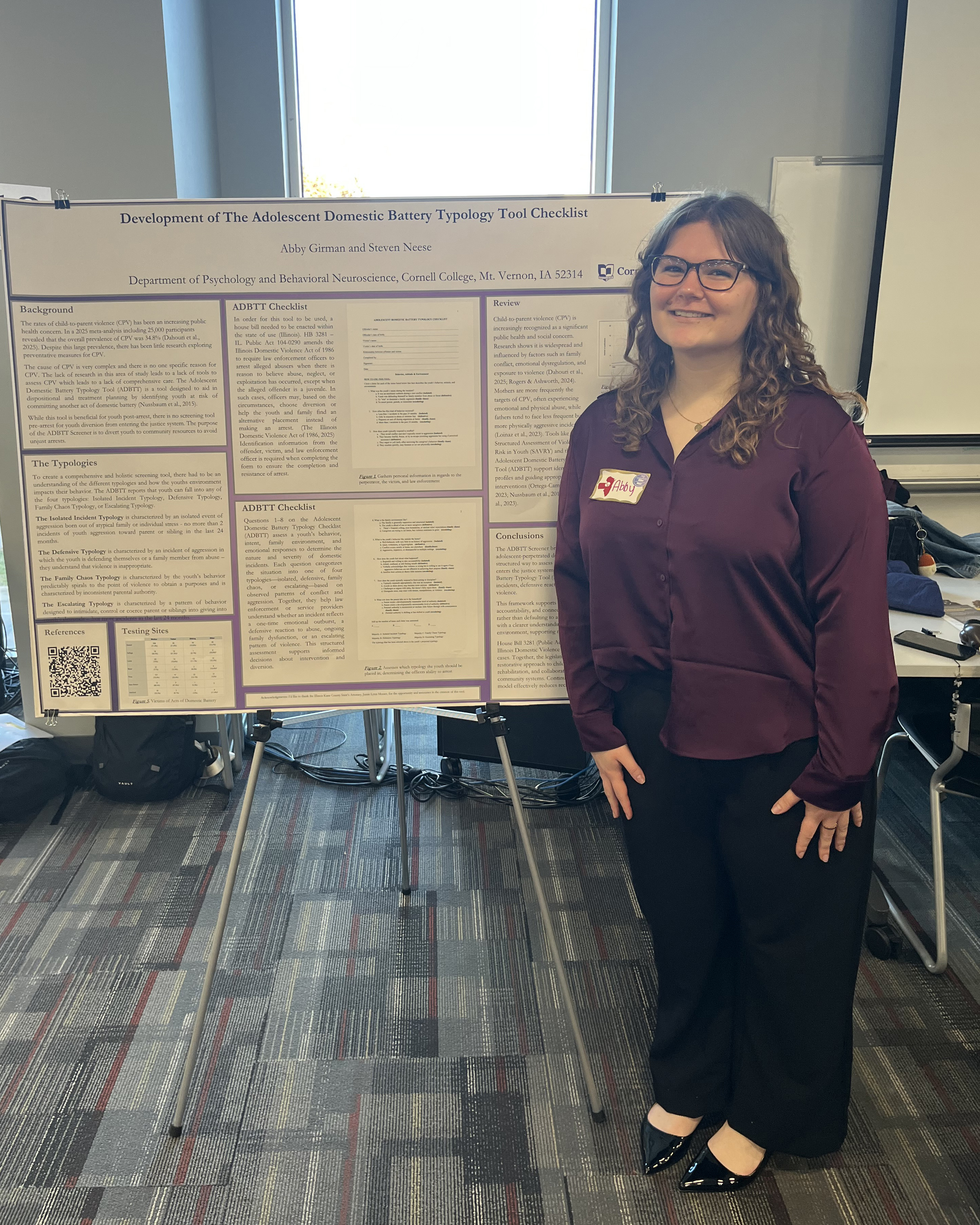 Abby Girman '26 stands next to the poster she used to give a presentation on her project at a conference.