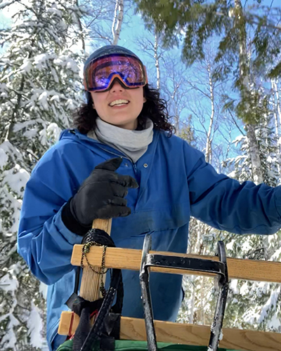 Natalie mushing on a wooden sled.