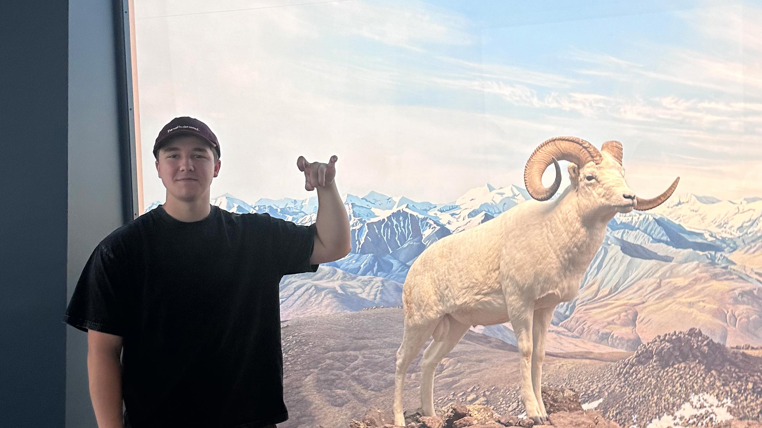Gavin Collyott '29 showing off the Rams hand signal next to a photo of a bighorn ram