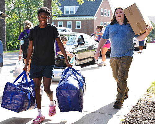 Students carry bags and boxes during move-in.