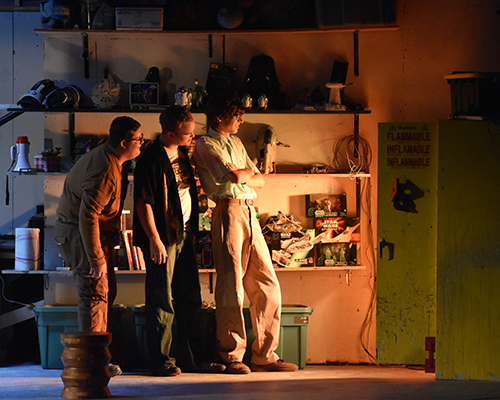 Three actors stand on stage