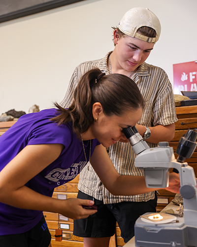 Two students work with a microscope.