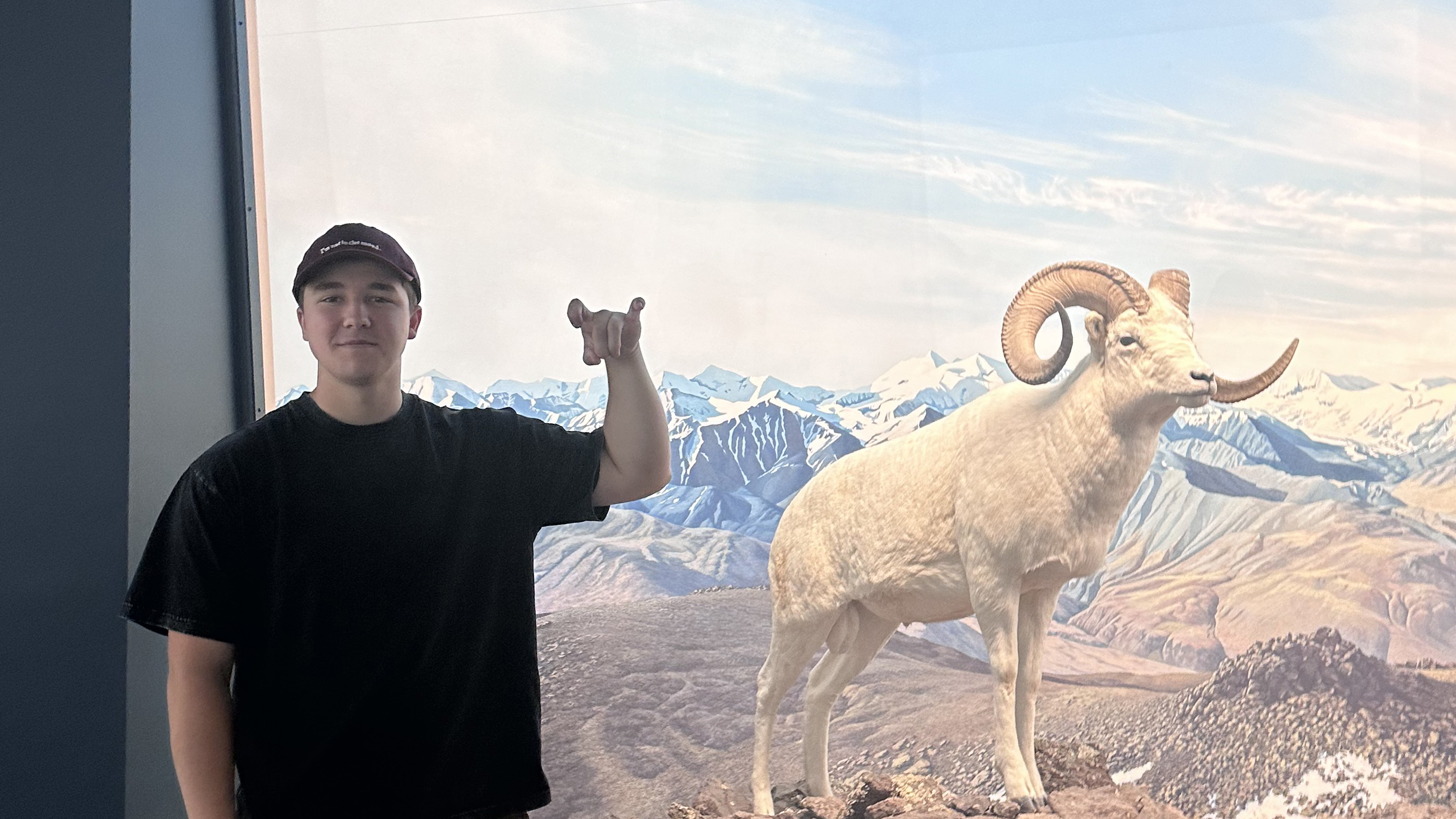 Gavin Collyott '29 showing off the Rams hand signal next to a photo of a bighorn ram