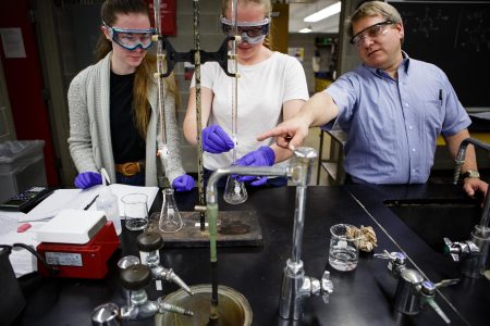 Two students and a professor work on a lab experiment