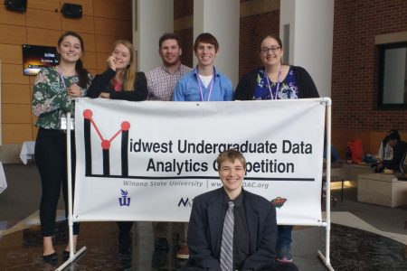 Cornell students posing by sign at a data analytics competition