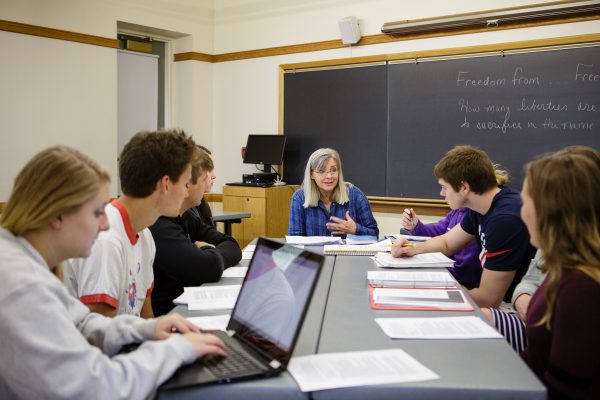 Students listening to professor at a table