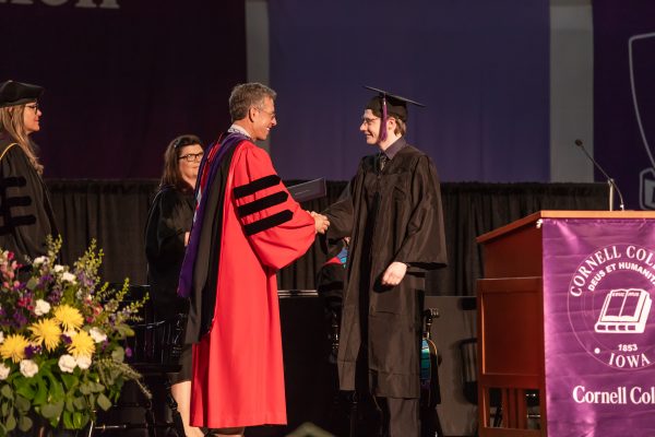 Mackenzie Crow '18 with President Jonathan Brand. They are on the stage shaking hands during graduation. 