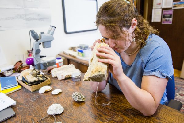 Kira Fish looks at coral with a hand lens