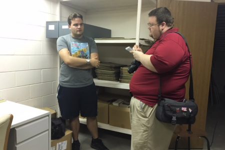 A reporter takes notes as he interviews a student.