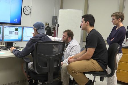 Students and Professor Walsh look at computer screen during research project