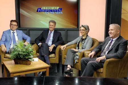 A panel of speakers smiles for a photo on the tv set