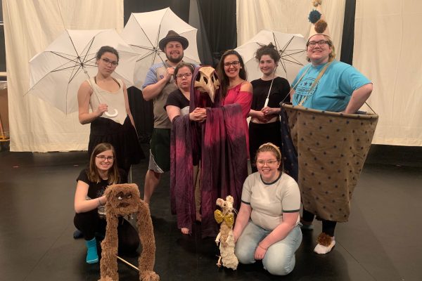 Students on stage with their puppets smiling at the camera