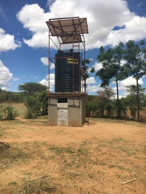 Photo of a water system in Tanzania with a well and solar panels.