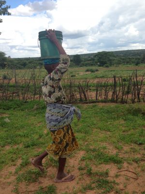 Woman walking with a bucket on her head in Africa.