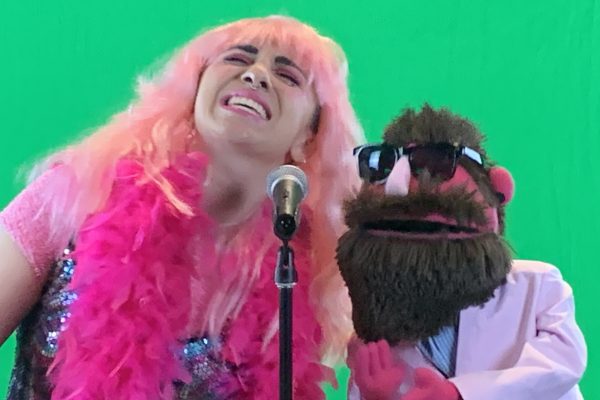 Jenna Makkawy and special guest, Mason Greve (puppet), sing a song by a green screen.